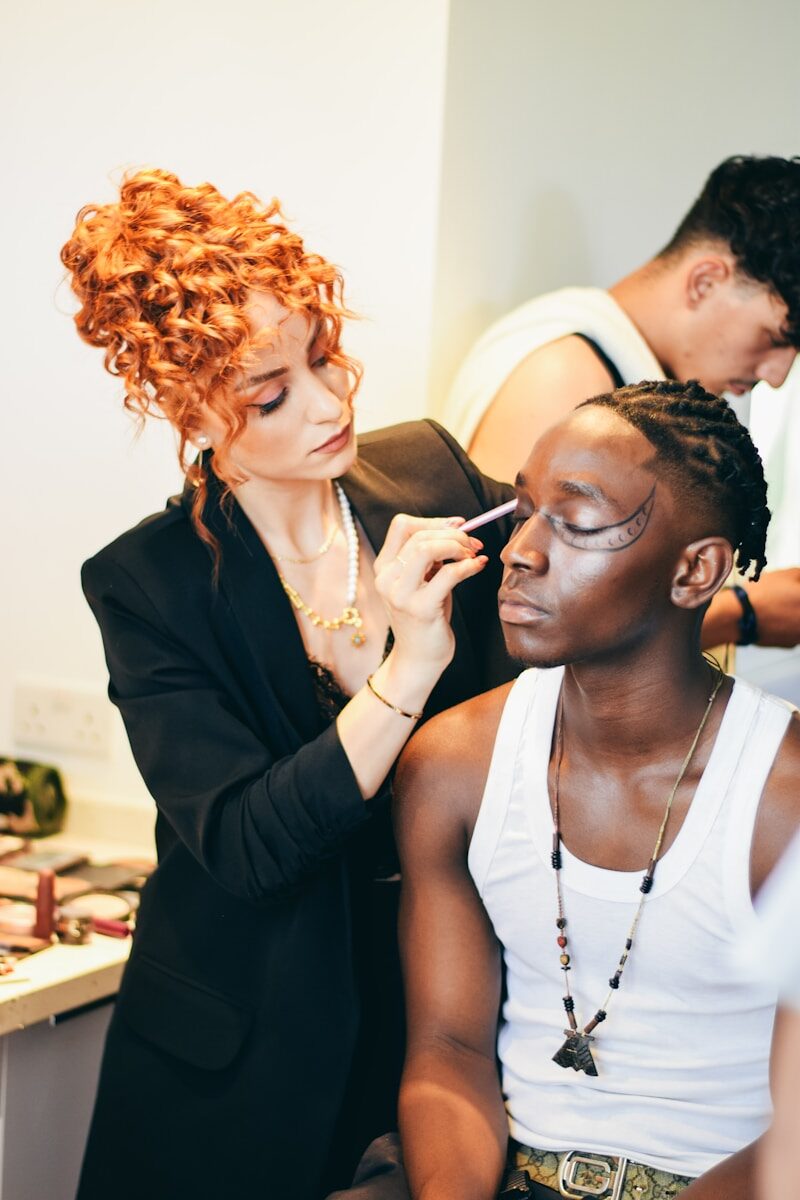Makeup artist applying makeup to a man's face.